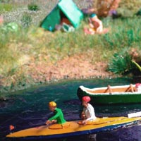 Boote auf dem Fluss mit lesender Person vor dem Zelt